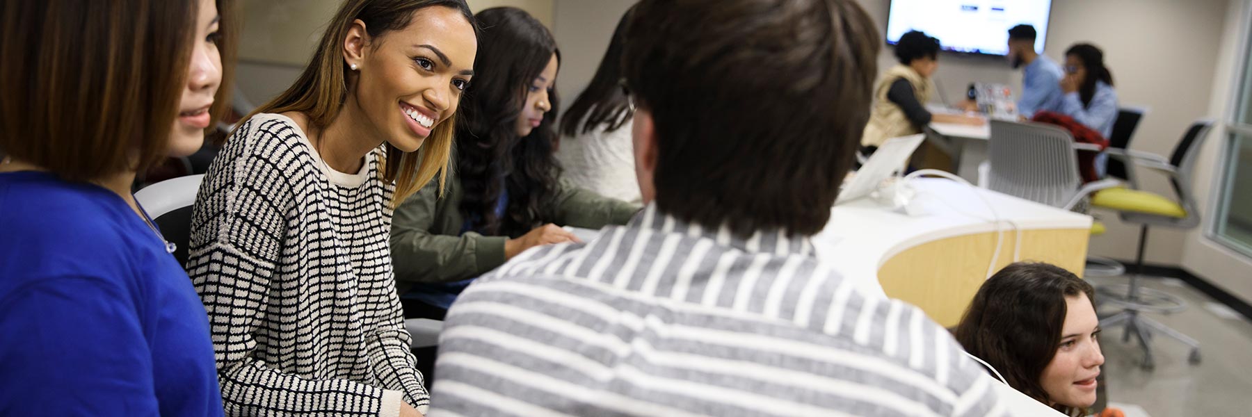 Students talk in a classroom.