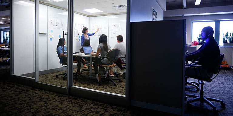 A group meets in a glassed-in conference room.